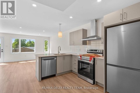 A modern kitchen with a refrigerator, oven, and sink.