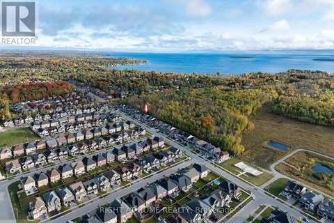 A bird's eye view of a residential neighborhood with houses, roads, and a body of water in the distance.