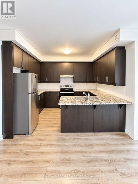 A modern kitchen with dark wood cabinets and a marble countertop.
