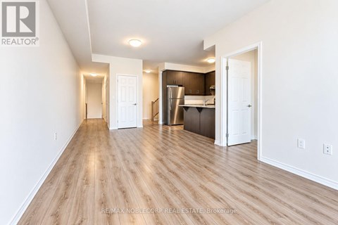 A spacious room with wooden flooring and white walls.