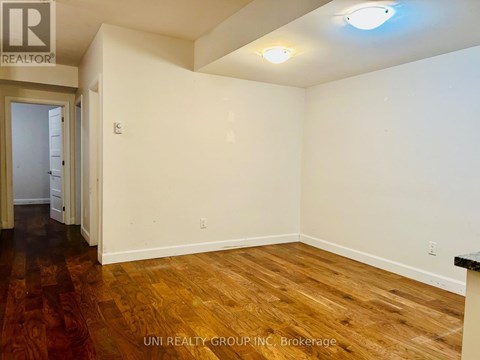 A room with wooden floors and white walls, with a door on the left and a light on the ceiling.
