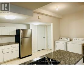 A kitchen with a stainless steel refrigerator, white cabinets, and a granite countertop.