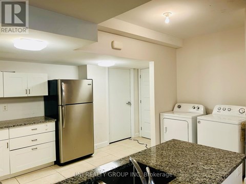 A kitchen with a stainless steel refrigerator, white cabinets, and a granite countertop.