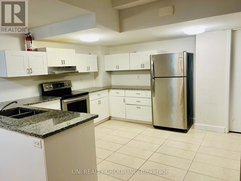 A kitchen with a refrigerator, oven, and cabinets.