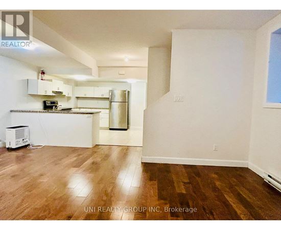 A kitchen with white cabinets and a wooden floor.