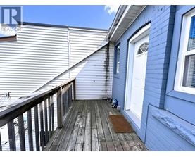 A wooden deck with a white door and a window.