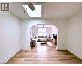 A spacious living room with a skylight and hardwood floors.