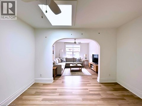 A spacious living room with a skylight and hardwood floors.