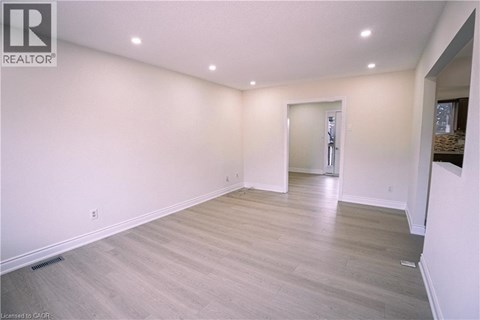 A spacious room with light wood flooring and white walls.