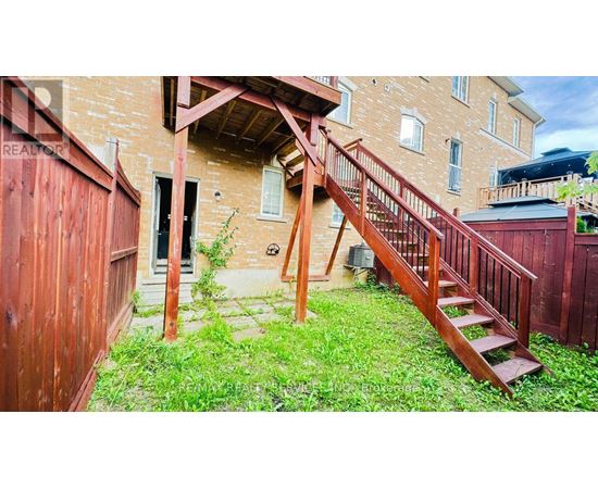 A wooden staircase leads up to a doorway in a brick building.