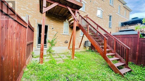 A wooden staircase leads up to a doorway in a brick building.