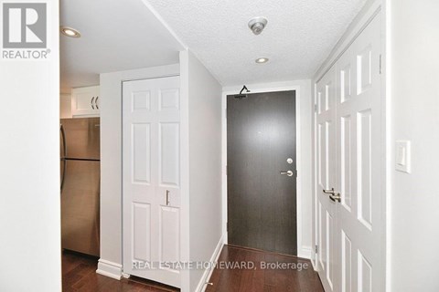 A brokerage sign is on the wall of a white hallway.