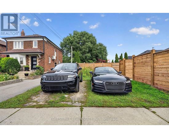 Two cars are parked in front of a house with a sign that says "REALTOR".