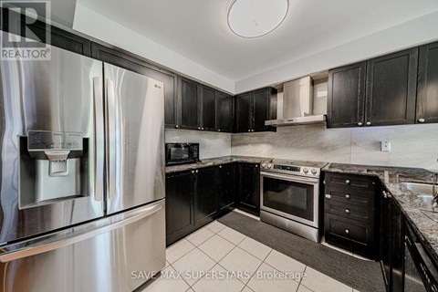 A kitchen with black cabinets and a stainless steel refrigerator.