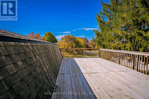 A wooden deck with a railing and trees in the background.