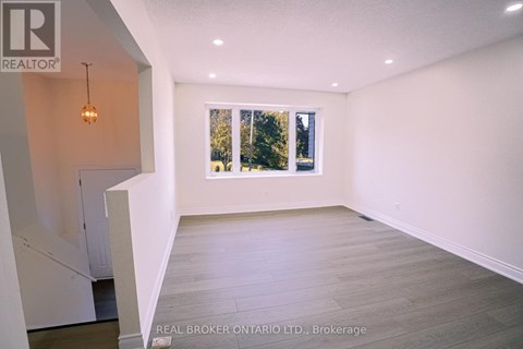 A spacious room with a large window and a white refrigerator.