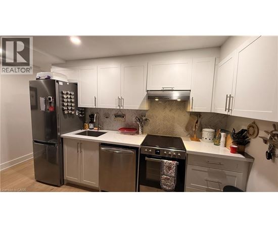 A kitchen with a refrigerator, oven, and sink.