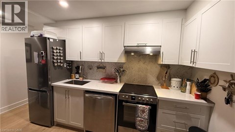 A kitchen with a refrigerator, oven, and sink.