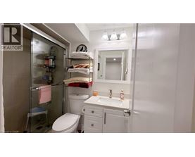 A small white bathroom with a toilet, sink, and shower.