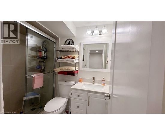 A small white bathroom with a toilet, sink, and shower.