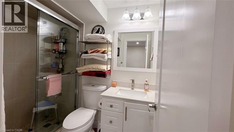 A small white bathroom with a toilet, sink, and shower.