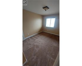 A room with a window and a light brown carpet.