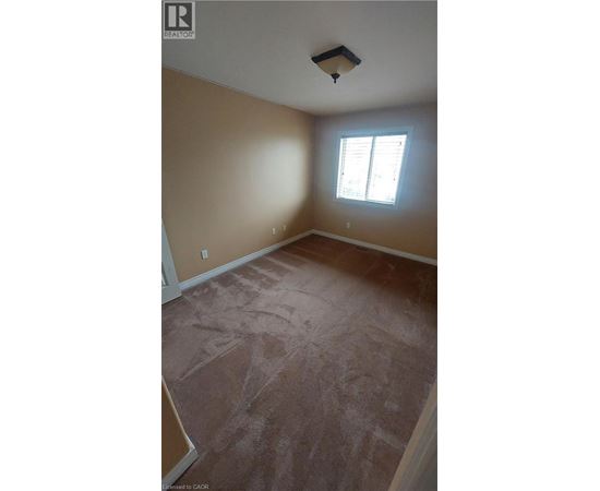 A room with a window and a light brown carpet.