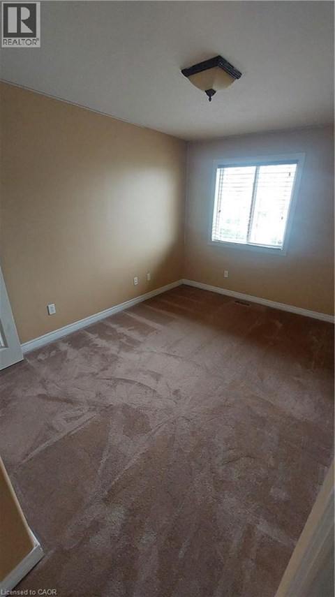 A room with a window and a light brown carpet.