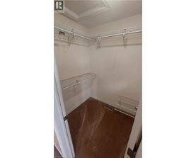 A walk in closet with white walls and shelves.