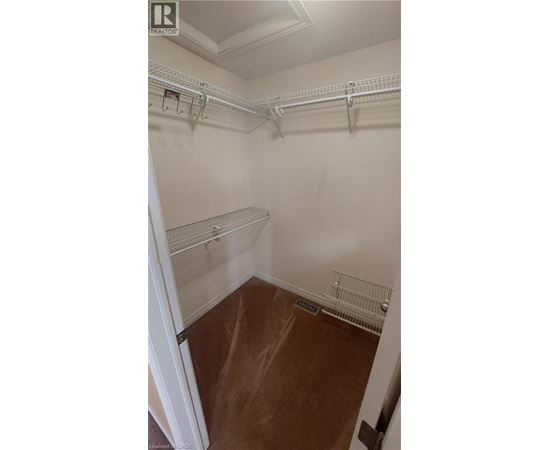 A walk in closet with white walls and shelves.