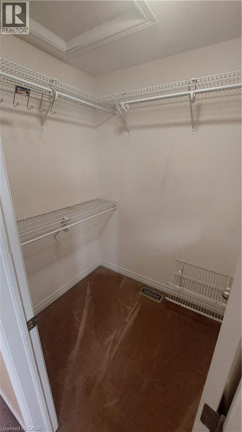 A walk in closet with white walls and shelves.