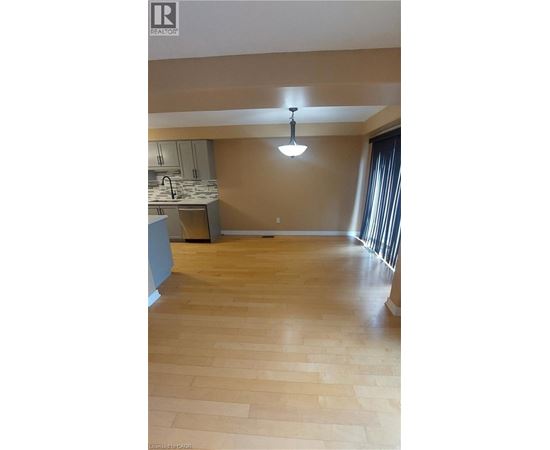 A kitchen with wooden floors and a hanging light fixture.
