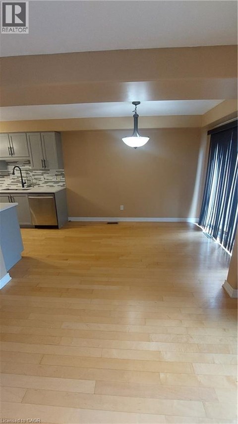 A kitchen with wooden floors and a hanging light fixture.