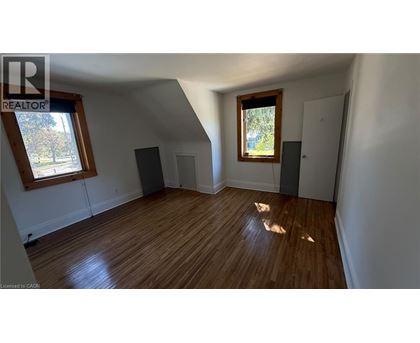 A room with wooden floors and white walls, with a window and a door visible.