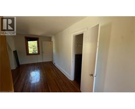 A room with wooden floors and white walls, with a door on the right side.