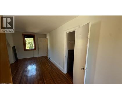 A room with wooden floors and white walls, with a door on the right side.