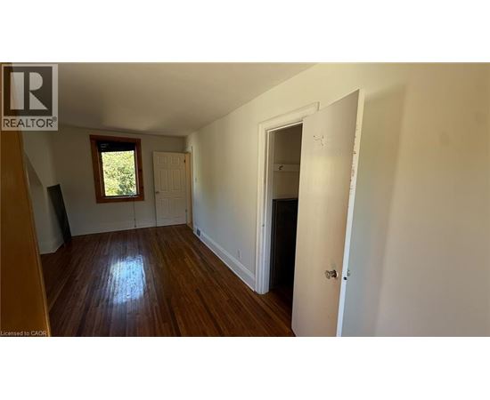 A room with wooden floors and white walls, with a door on the right side.