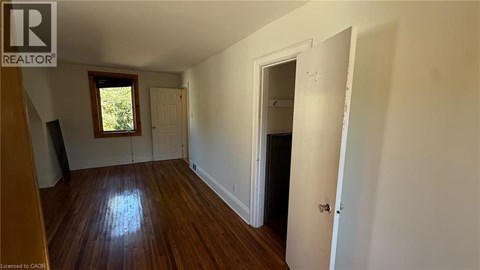 A room with wooden floors and white walls, with a door on the right side.