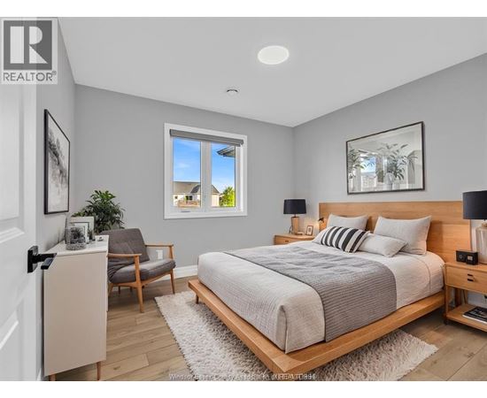 A bedroom with a large bed, a chair, and a window.