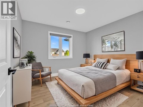 A bedroom with a large bed, a chair, and a window.