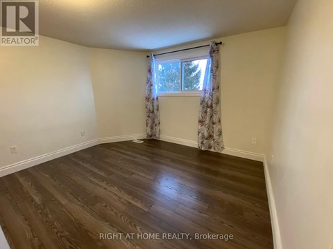 A room with wooden flooring and a window with curtains.