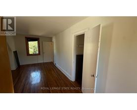 A room with wooden floors and white walls, with a door on the right side.