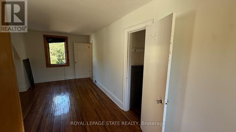A room with wooden floors and white walls, with a door on the right side.