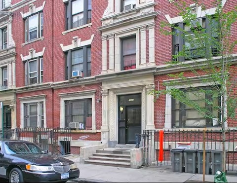 A black car is parked in front of a red brick building.