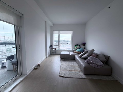 A living room with a grey couch and a large window.