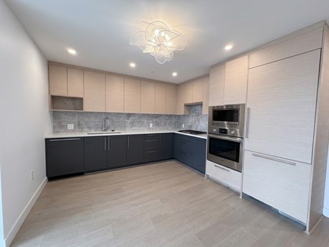 A modern kitchen with a large island and stainless steel appliances.