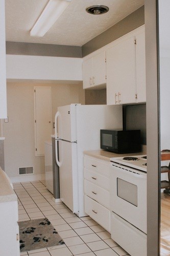 A kitchen with white appliances and cabinets.