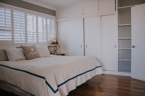 A bedroom with a bed, pillow, and a nightstand.