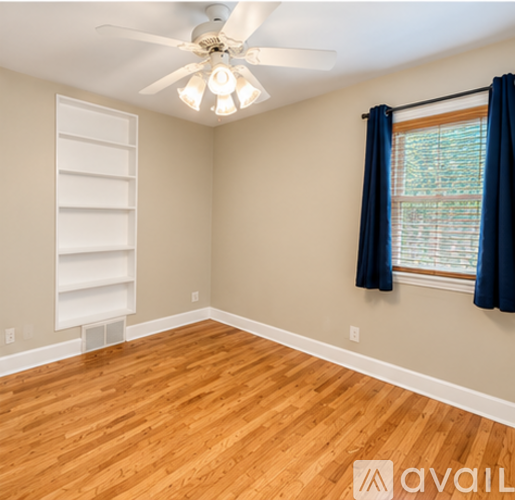 A room with a wooden floor and a window with blue curtains.