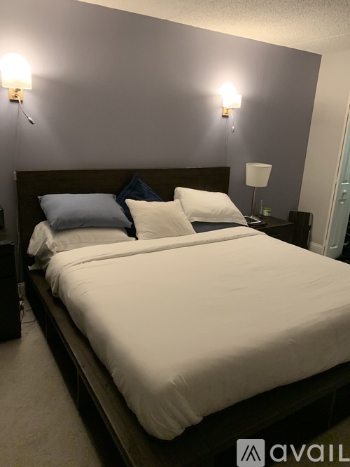 A bed with white sheets and two blue pillows.